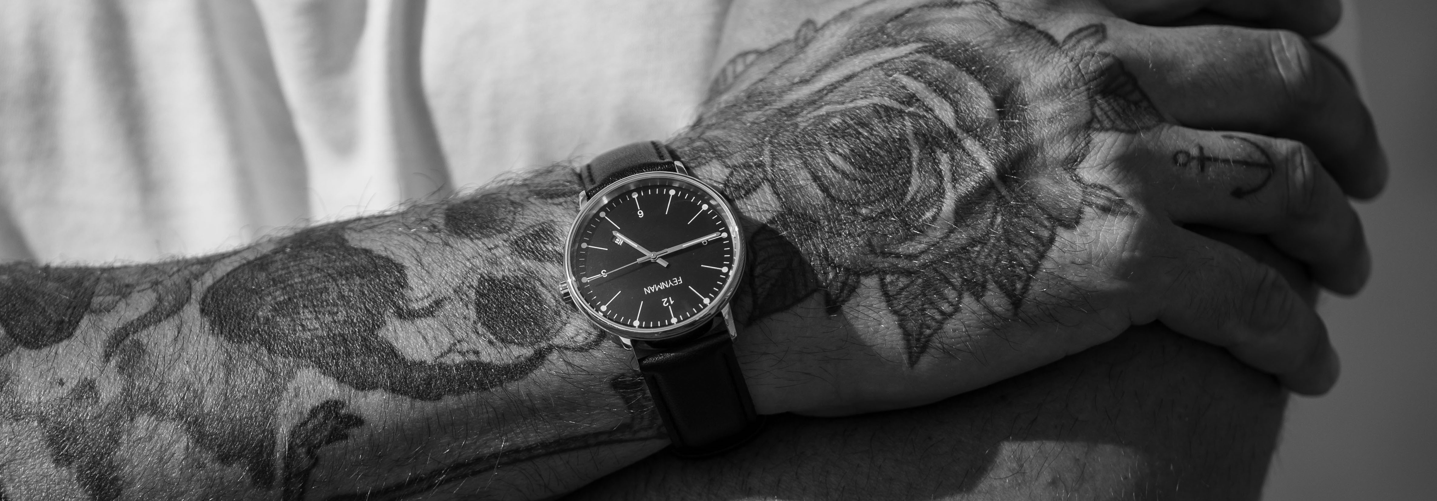Photo of a tattooed arm wearing a Feynman CWII wristwatch