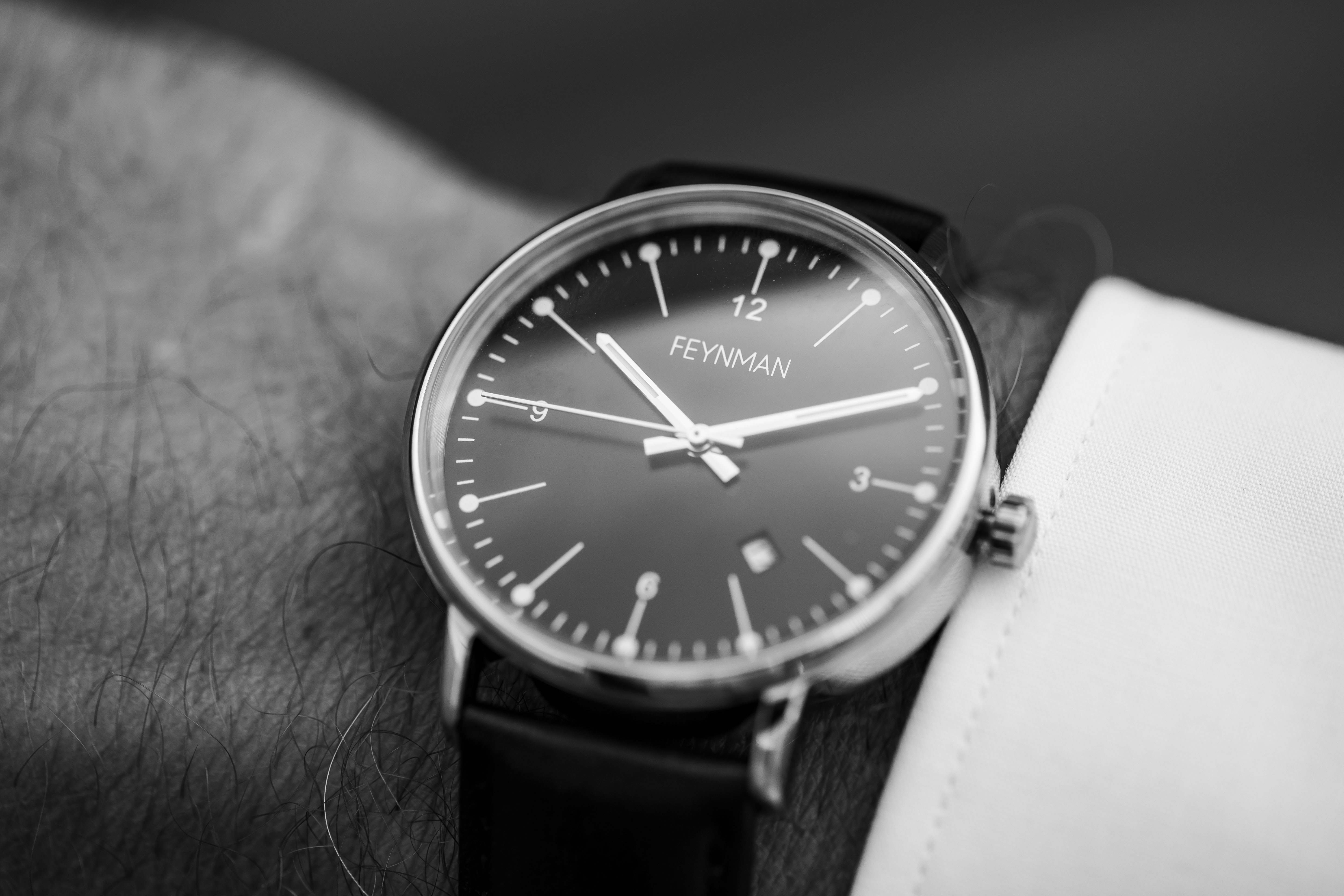 Photo of the wrist of a man, wearing a shirt and a Feynman CWII watch